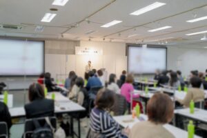西川株式会社様で実施した笑顔ワークショップの様子。笑顔専門家 川野恵子が登壇し、笑顔・コミュニケーション・接客力向上について講演を行う企業研修風景。